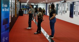 Mulheres observam exposição "O voto no Brasil", no edifício-sede do TSE, em Brasília