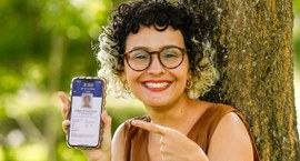 Jovem eleitora aponta para o celular com o aplicativo e-Título em destaque
