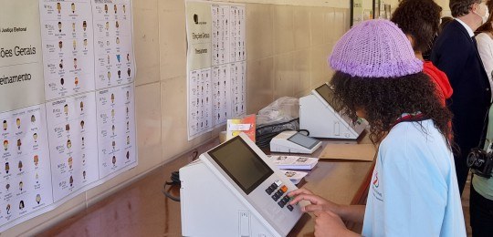 Adolescente vota na urna eletrônica Adolescente votando em uma urna eletrônica