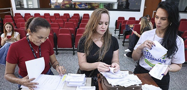 A foto mostra servidoras da Justiça Eleitoral preparando as urnas que serão utilizadas na audito...