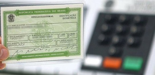 Foto de uma urna eletrônica à direita e um título eleitoral à esquerda