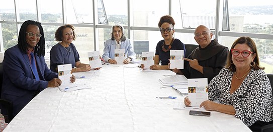 No centro da mesa está a ministra Carmen Lúcia conduzindo a conversa. Ao redor dela, outras cinc...