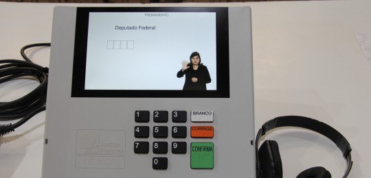 Foto da tela da urna eletrônica com imagem de uma mulher intérprete de Libras.