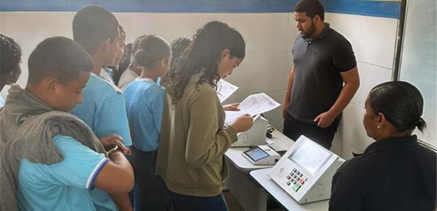JE pelo Brasil TRE-SE - 12.12.2025 A imagem mostra um grupo de estudantes e adultos em uma sala, provavelmente uma escola, particip...