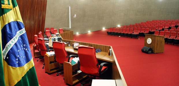 A imagem mostra o interior do plenário no TSE. Em primeiro plano, à esquerda, aparece parte da b...