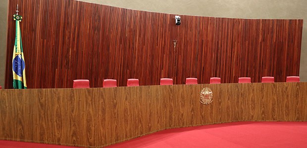 Plenário do Tribunal Superior Eleitoral. Há uma grande bancada de madeira em formato curvo, com ...