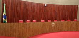 Plenário do Tribunal Superior Eleitoral. Há uma grande bancada de madeira em formato curvo, com ...
