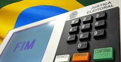 Urna eletrônica com imagem ao fundo da Bandeira do Brasil