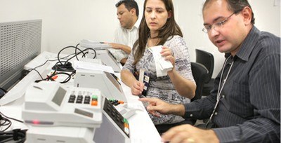 Equipe preparando a mesa para os testes de urna eletrônica.