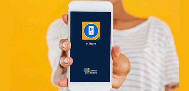 Pessoa segura um celular com o aplicativo oficial e-Título aberto na tela